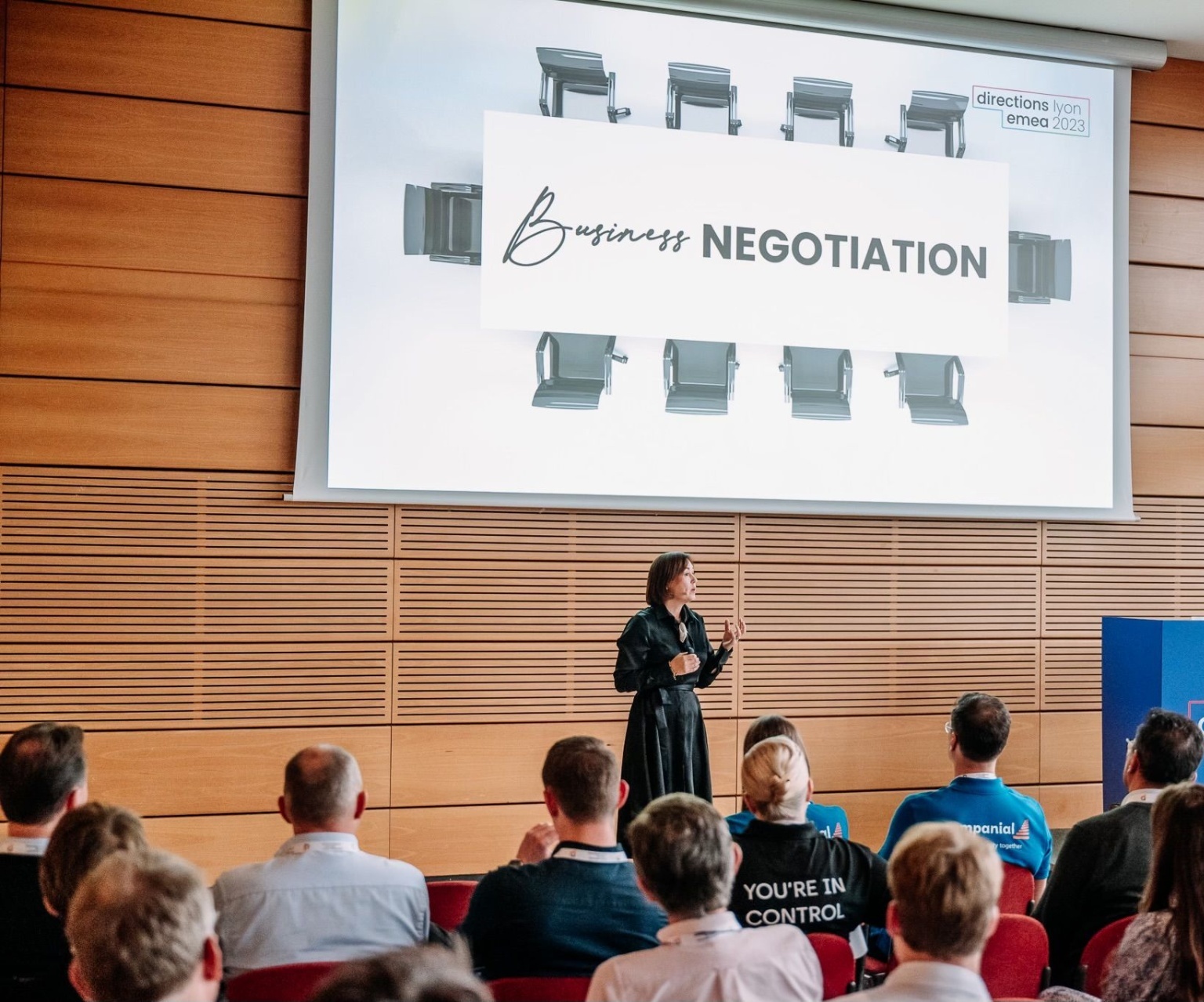 Keynote speaker on stage under a single warm spotlight addressing an audience